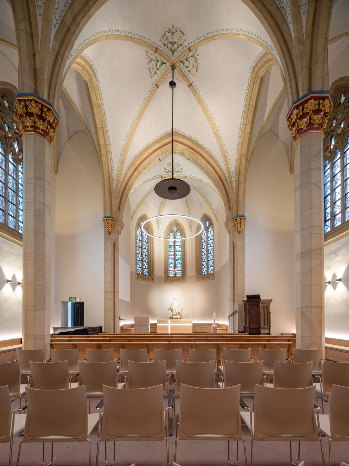 Der Blick ins Kirchenschiff Richtung Altar. Stuhlreihen und Leuchten sind zu sehen.